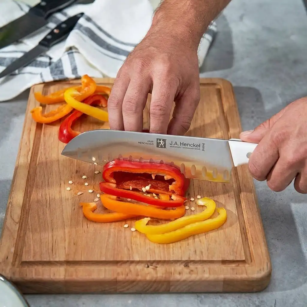 Sharp chef's knife slicing through fresh bell peppers on a rustic wooden cutting board.